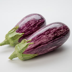 Angled view of Annina eggplants showing glossy cream and purple streaked teardrop fruit on white background
