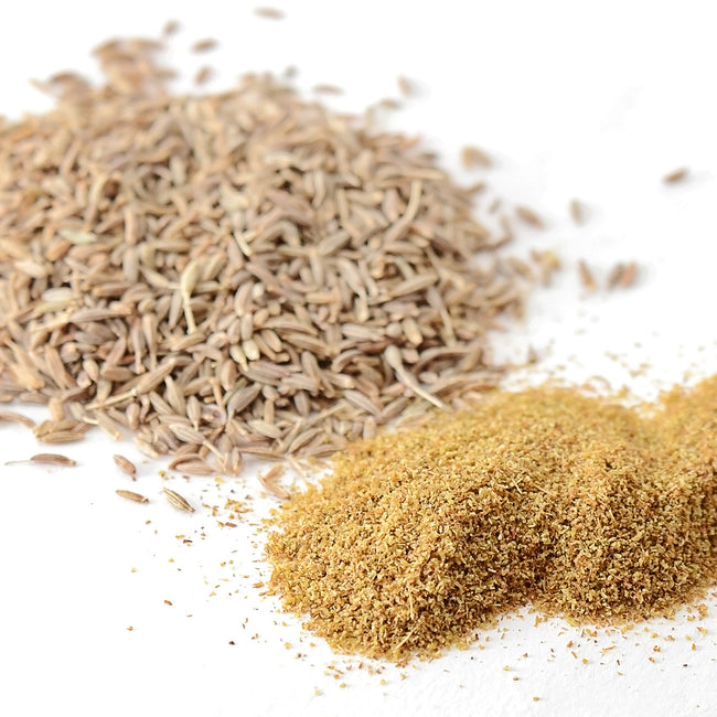 Close up of whole cumin seeds and ground cumin showcasing seed texture and powdered spice on a white background