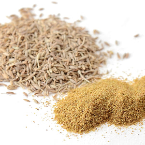 Close up of whole cumin seeds and ground cumin showcasing seed texture and powdered spice on a white background
