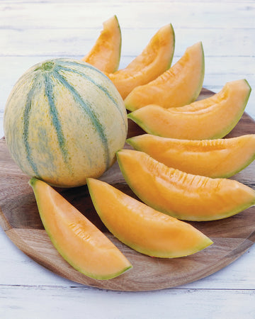 Whole and sliced Alvaro melon showing orange flesh and yellowish-tan skin with green striping on a wooden board