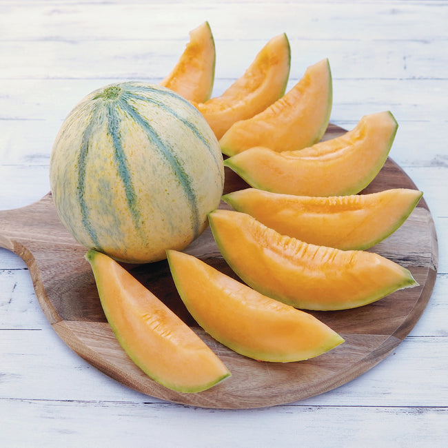 Whole and sliced Alvaro melon showing orange flesh and yellowish-tan skin with green striping on a wooden board