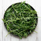 Overhead view of Bellezia arugula showcasing dark green, deeply serrated leaves on a round black plate over white wood