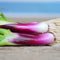 Close-up of Red Baron bunching onion showing burgundy stalks and white bulb ends on a wooden surface
