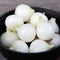 Close-up of Pacific Pearl onion bulbs showing small smooth white marble-sized onions in a dark bowl