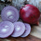 Front view of Red Mountain storage onions showing whole deep-red bulbs and sliced rings revealing purple-white interior on wooden surface