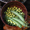 Top-down view of Lincoln pea pods and shelled green peas in a brown ceramic bowl on a rustic surface
