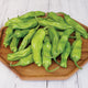Close-up of Takara Shishito peppers showing slender light green pods on a wooden plate