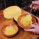 Three-quarter view of halved spaghetti squash showing stringy, spaghetti-like flesh scooped into a bowl on a cutting board