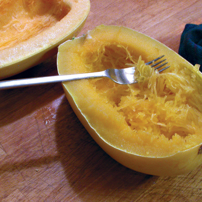 Halved spaghetti winter squash showing stringy, spaghetti-like flesh on a wooden surface