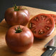 Front view of Darkstar tomato showcasing pleated beefsteak shape and deep purple-red color with neutral background