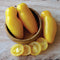 Close-up of Banana Legs tomatoes showing elongated golden-yellow fruits with sliced cross-sections on a wooden surface