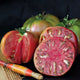 Close-up of Black Tomato sliced to show rosy-pink interior and darkened shoulders on a cutting board