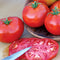 Close-up of Burbank Slicing tomatoes showing whole deep-red fruits and sliced interior on a wooden board with a knife