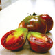 Close-up of Japanese Trifele Black tomato showing dark mahogany fruit with green-streaked shoulders and sliced interior