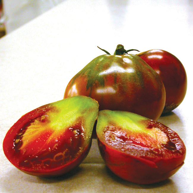 Close-up of Japanese Trifele Black tomato showing dark mahogany fruit with green-streaked shoulders and sliced interior