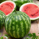 Front view of Cal Sweet Bush watermelon, whole and halved to show red flesh and black seeds on a wooden surface