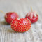 Close-up of Marshall strawberry showing heart-shaped red fruit with yellow seeds on a weathered wood surface