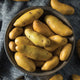 Close-up of Austrian Crescent potatoes showing long thin crescent-shaped pale yellow skins in a dark bowl
