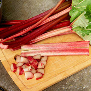 Front view of Crimson Red rhubarb showing deep red tender stalks and diced pieces on a wooden cutting board