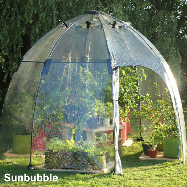 Front view of Sunbubble dome greenhouse showcasing clear PVC cover, zippered door, and plants inside on a lawn