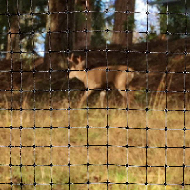 Close-up front view of black deer fencing showing 1-inch square mesh pattern with a blurred deer and trees behind
