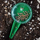 Top-down view of Dial Seed Sower showing clear numbered dial and filled seed compartment on potting soil