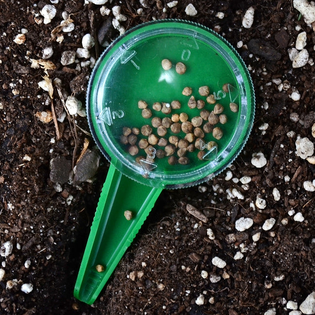 Top-down view of Dial Seed Sower showing clear numbered dial and filled seed compartment on potting soil