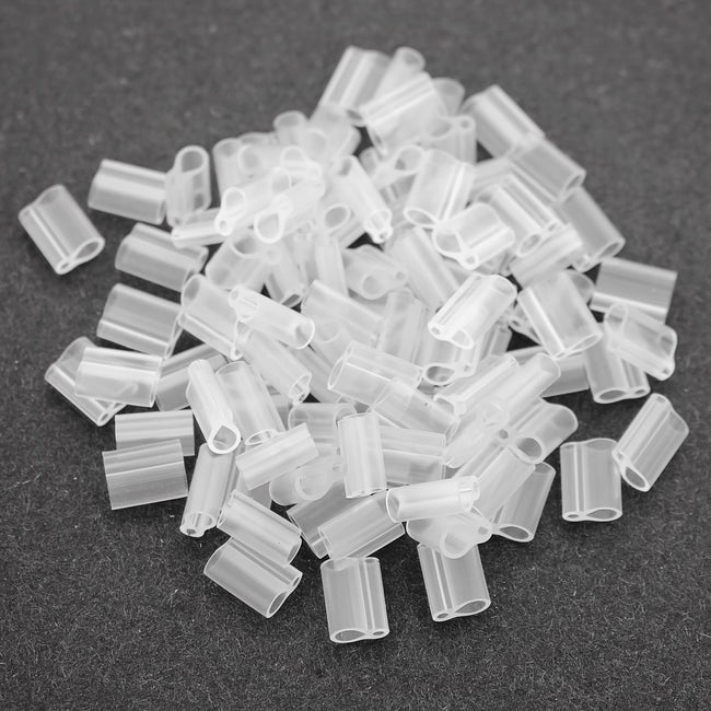 Top-down view of translucent silicone grafting clips piled on a dark background, 1.7 mm diameter