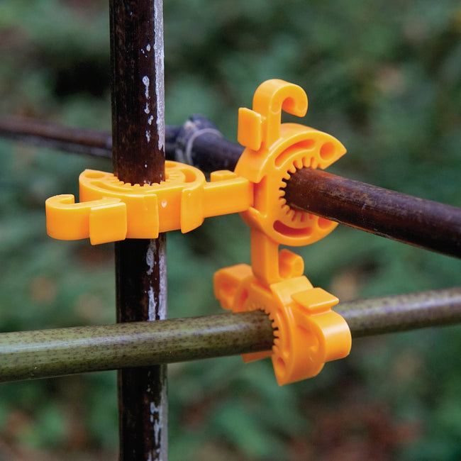 Close-up of tangerine C-Bite stake clips showcasing interlocking grips and hooks attached to metal garden stakes