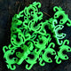 Overhead view of lime green C-Bite stake clips piled on dark wood, showing C-shaped interlocking design with hooks and holes