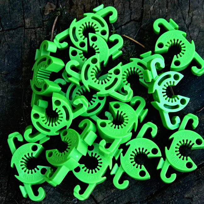Overhead view of lime green C-Bite stake clips piled on dark wood, showing C-shaped interlocking design with hooks and holes