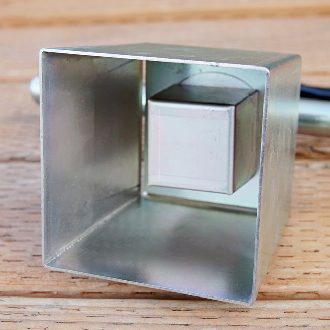 Front view of 4-inch metal soil blocker showing square pressing cavity on white background