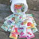Angled view of Territorial's Victory Garden seed collection showing assorted seed packets fanned around a white tin on a light background